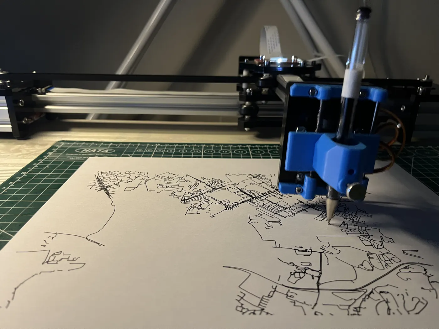 Mid-plot: dense road-map linework building up under the pen.